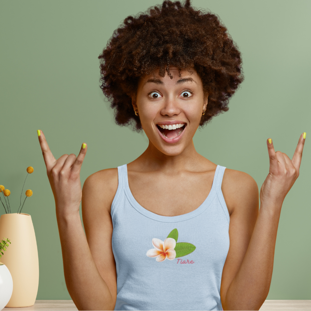 A woman wearing a light blue micro-rib tank top with a tiare flower design, smiling and making a peace sign with her hands.