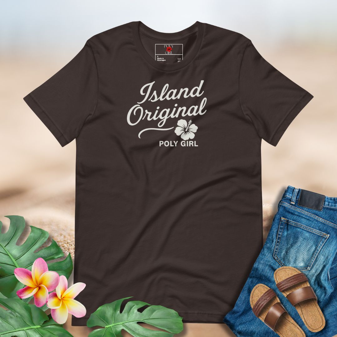Brown t-shirt with 'Island Original Poly Girl' text, surrounded by tropical leaves and sandals on a light background