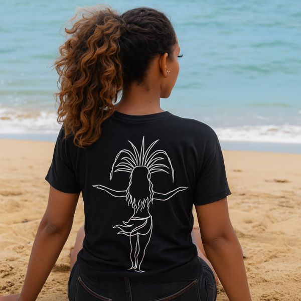 Woman wearing a black tshirt with whie line art of tahitian dancer sitting on a beach