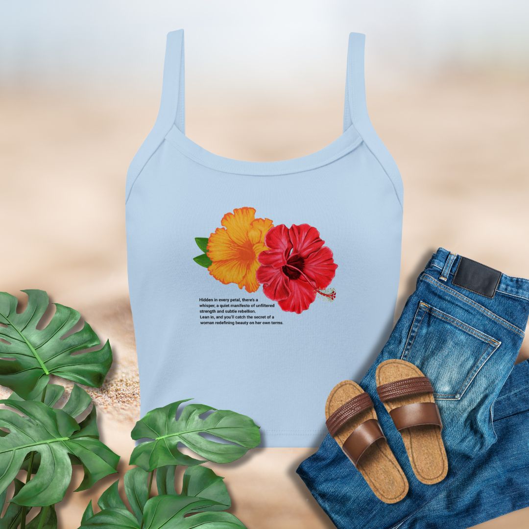 Light blue tank top with floral design on a beige background with plants and jeans.