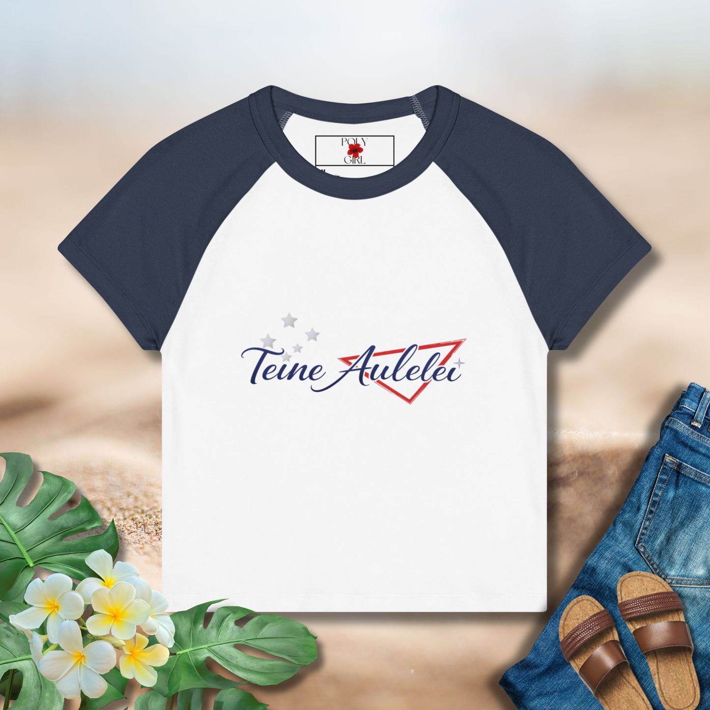 Navy and white baseball shirt with 'Teine Aulelei' logo on a sandy background with flowers and sandals.