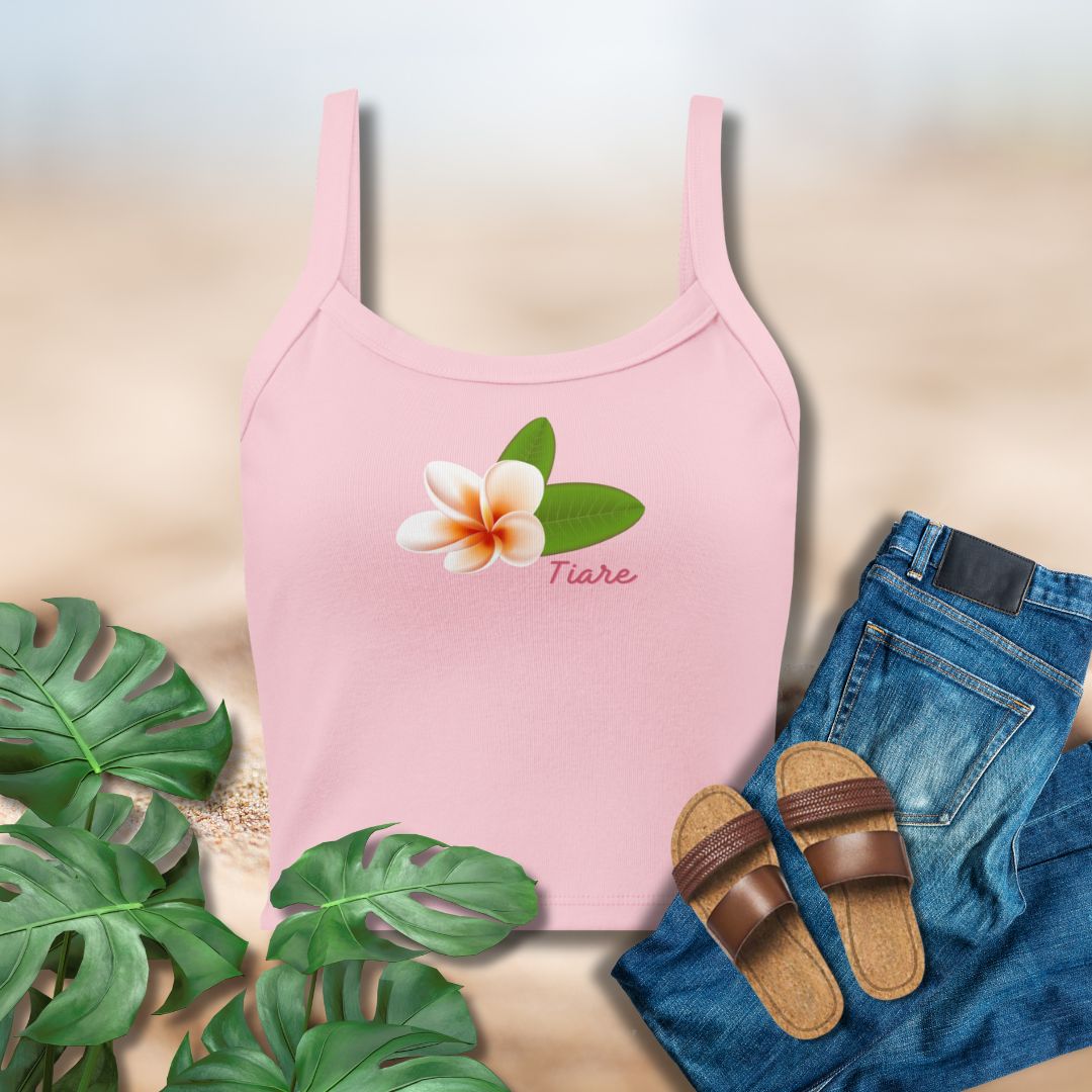 Pink tank top with frangipani design, jeans, sandals, and leaves on a light background