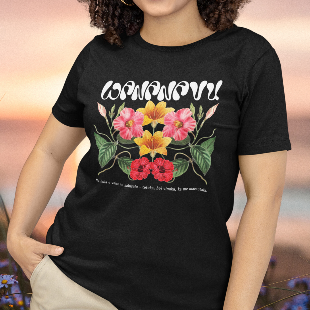 A woman wearing a black t-shirt with a vibrant floral design and the text 'WANANAVU' on the front.