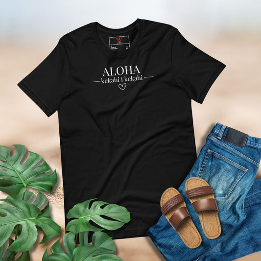 Black t-shirt with "Aloha kekahi i kekahi" text, sandals, and jeans on a neutral background