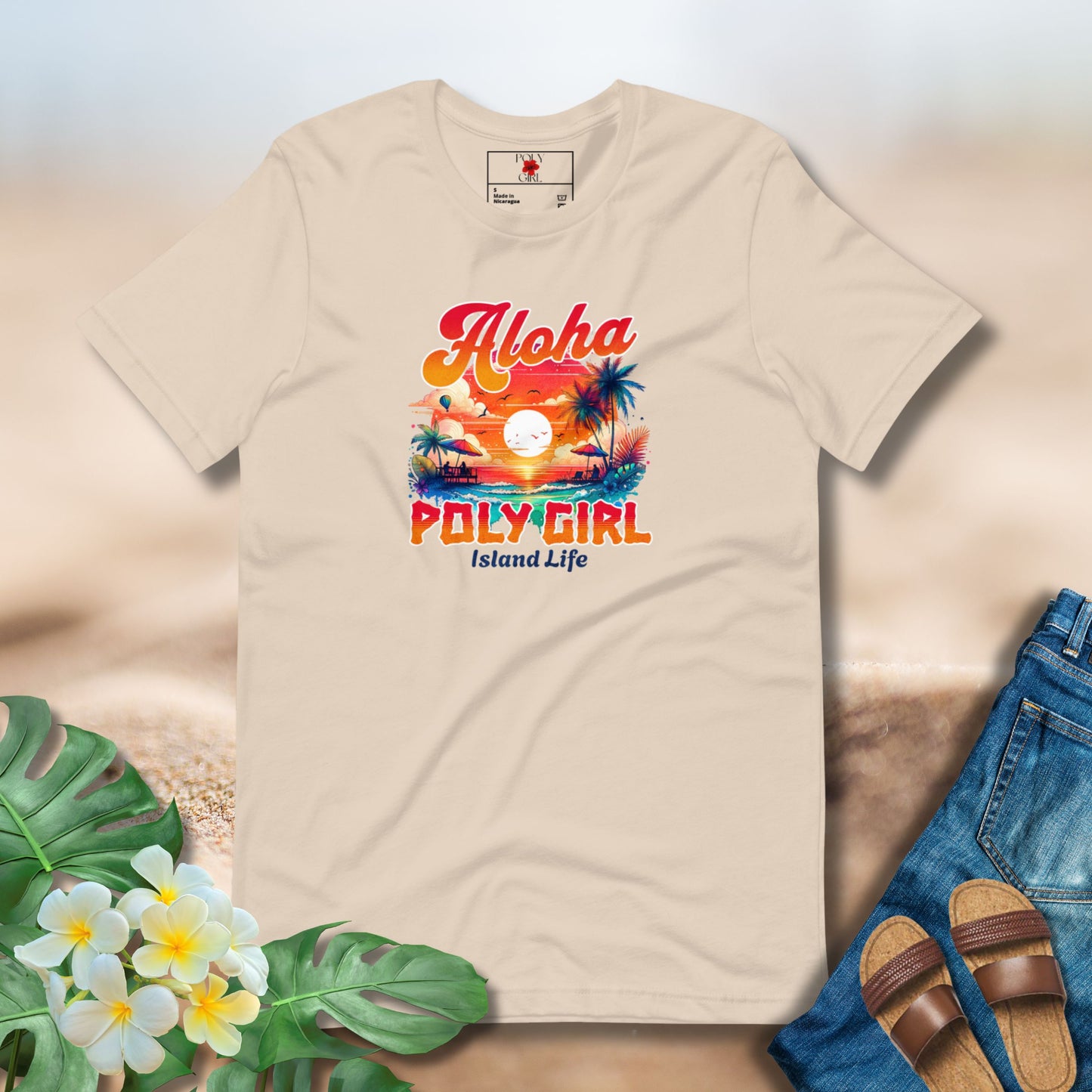 Beige t-shirt with 'Aloha Poly Girl Island Life' design on a light background with flowers and jeans.