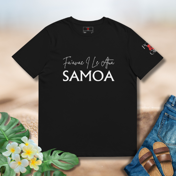 Black t-shirt with 'Fa'avae I Le Atua Samoa' text on a wooden surface with flowers and sandals.