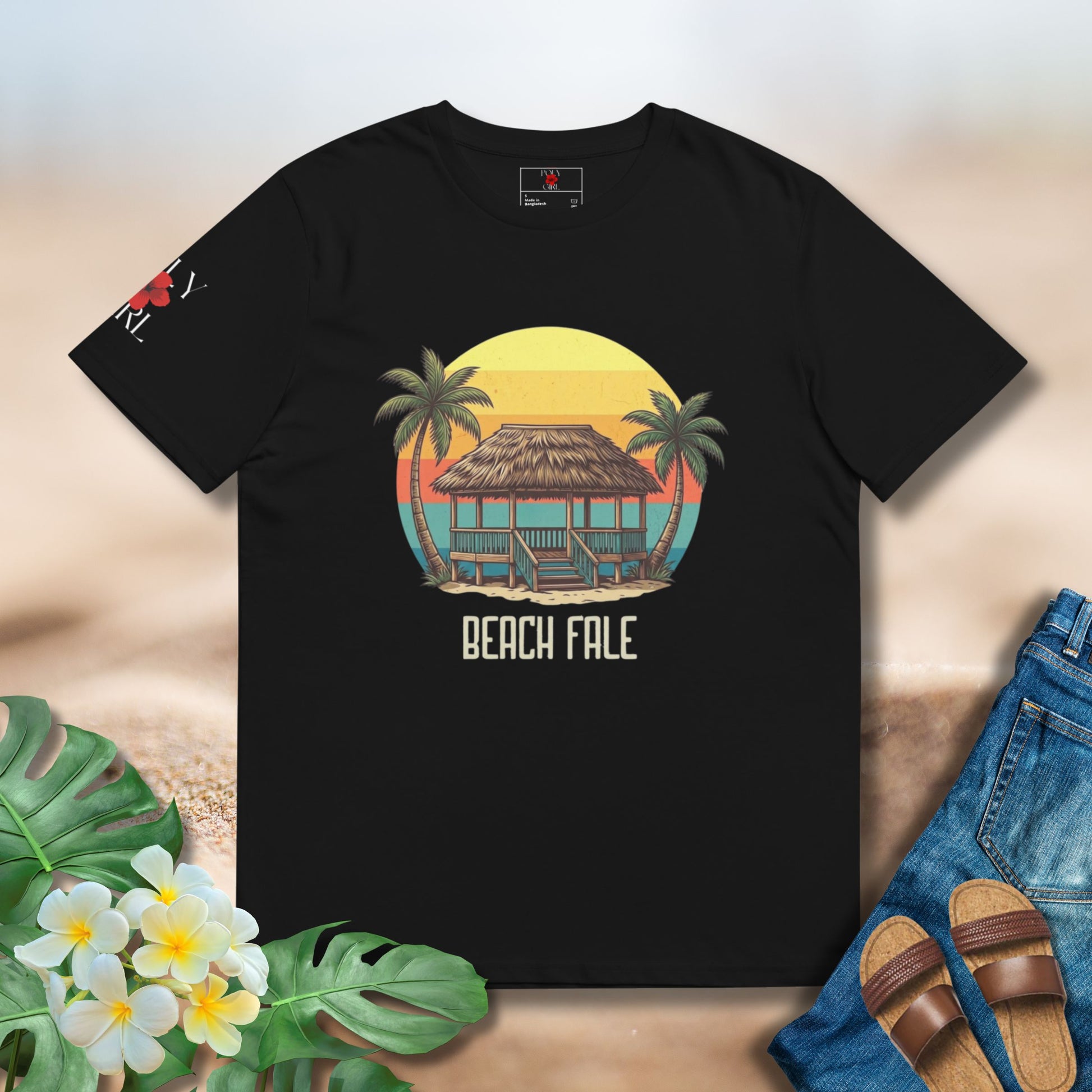 Black t-shirt with 'Beach Fale' design featuring a hut and palm trees, placed on a sandy background with floral and shoe elements.