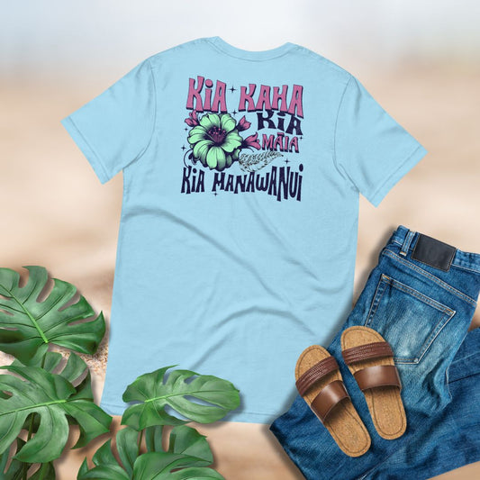 Light blue t-shirt with Maori inspired design by Poly Girl paired with jeans and sandals on a neutral background.