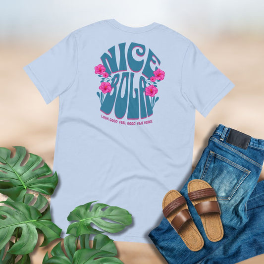 Light blue t-shirt with Fijia slang 'Nice Bola' design, paired with jeans and sandals on a neutral background. 