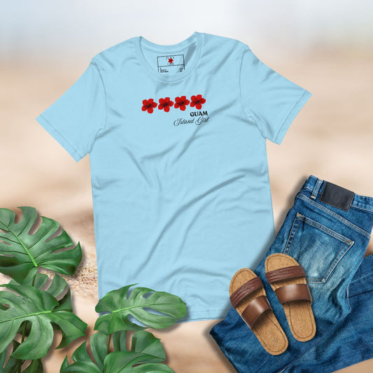 Light blue t-shirt with r red hibiscus design and the words "Guam, Island Girl", paired with jeans and sandals on a neutral background.