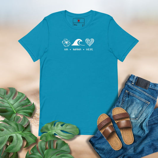 Blue t-shirt with a wave and heart design, surrounded by green leaves, sandals, and jeans on a beige background.