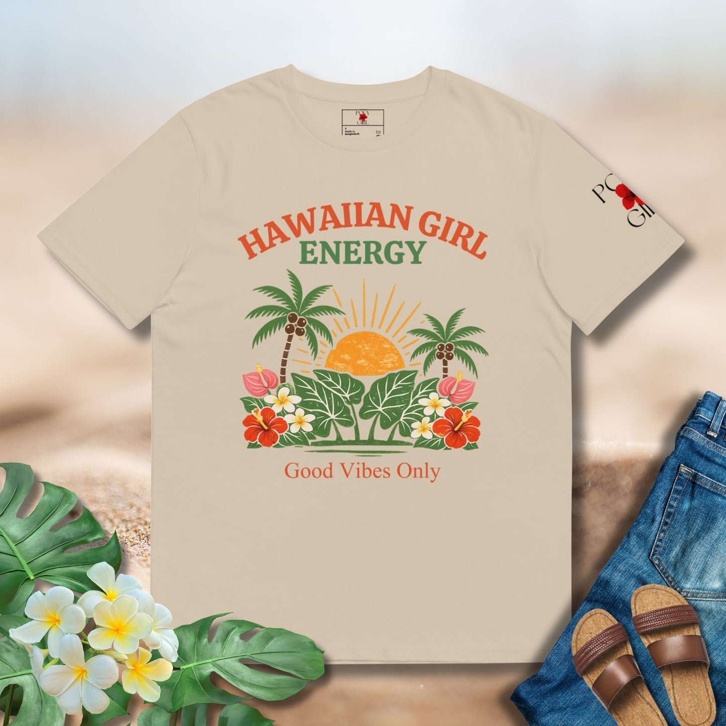 Beige t-shirt with 'Hawaiian Girl Energy' design on a neutral background with flowers and jeans.