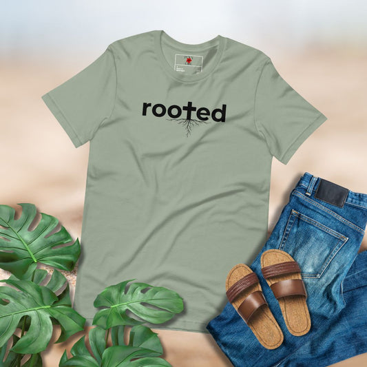 Ladies Sage Colored Tshirt with Rooted design by Poly Girl paired with jeans and sandals on a neutral background