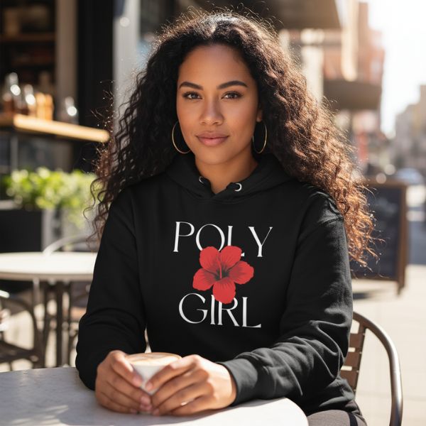 Woman wearing a black hoodie with 'POLY GIRL' and a red flower design, sitting outdoors. Poly Girl, The Island Girl's Brand. 