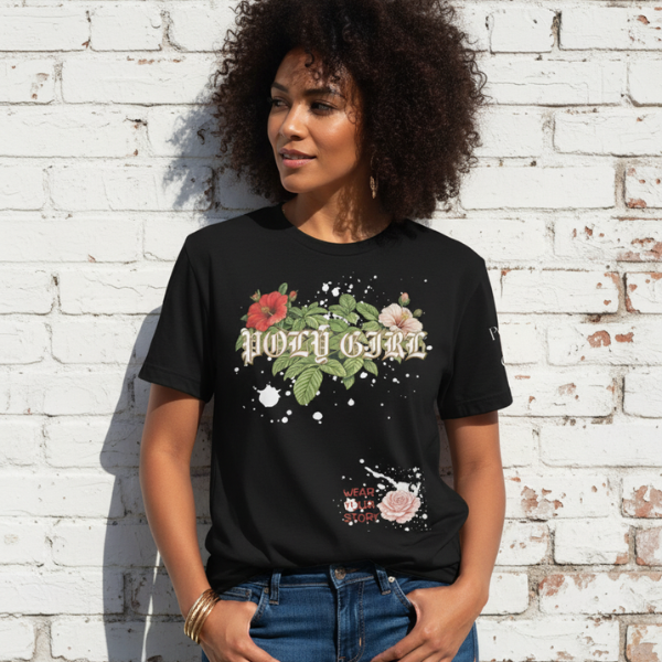 Woman wearing a black t-shirt with floral graphics and text against a white brick wall.