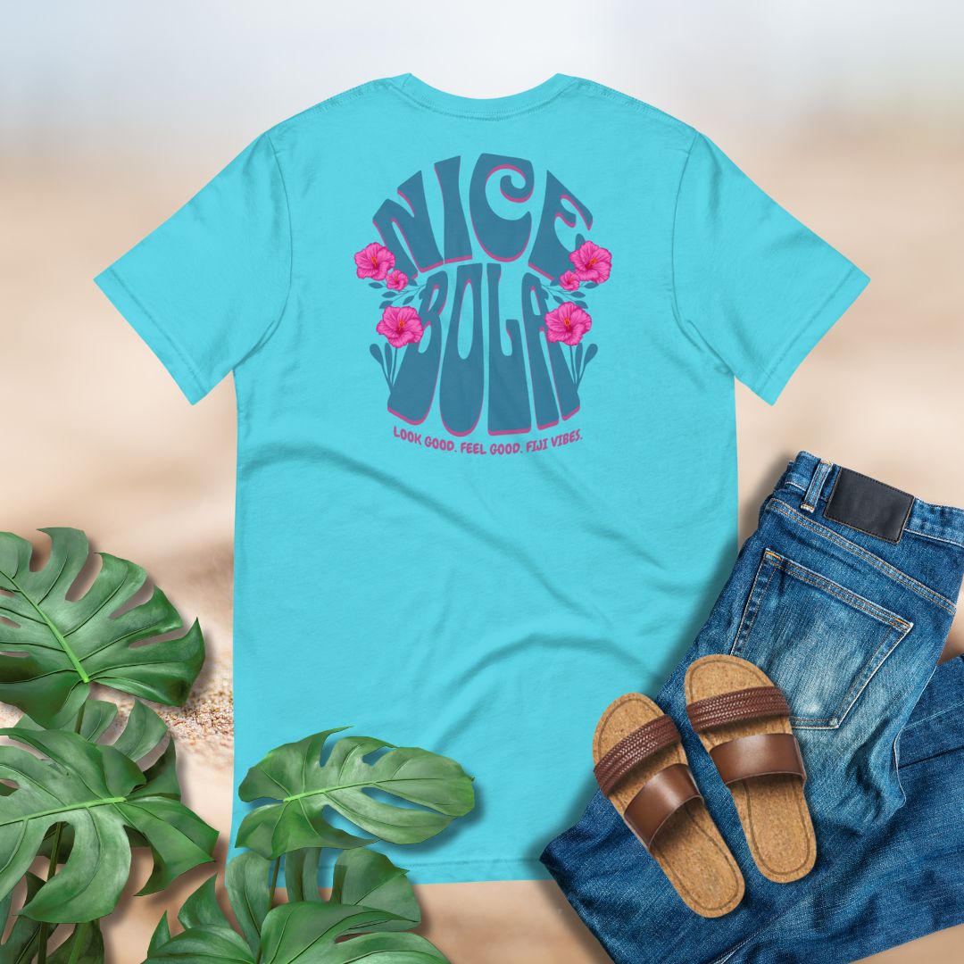 Turquoise t-shirt with floral design and text, paired with jeans and sandals on a neutral background. Nice Bola Fijian tee by Poly Girl
