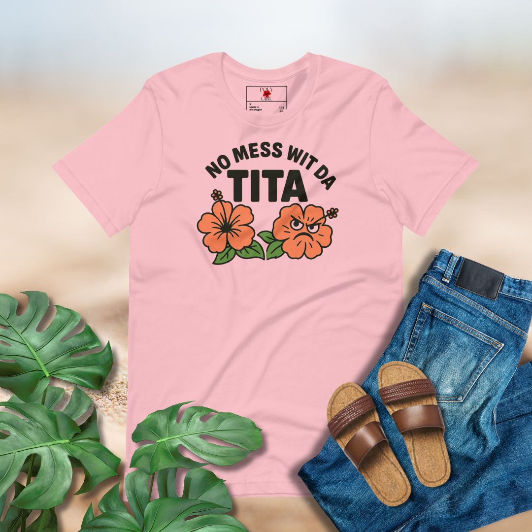 Pink t-shirt with 'No Mess Wit Da Tita' text and flowers, paired with jeans and sandals on a light background.