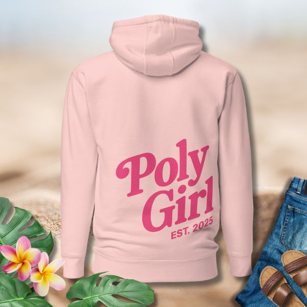 Pink hoodie with 'Poly Girl EST. 2025' text on a neutral background with plants and sandals.