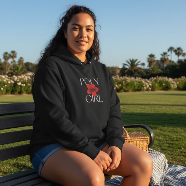Woman wearing a black hoodie with 'Poly Girl' text and a red flower graphic, sitting on a bench outdoors.