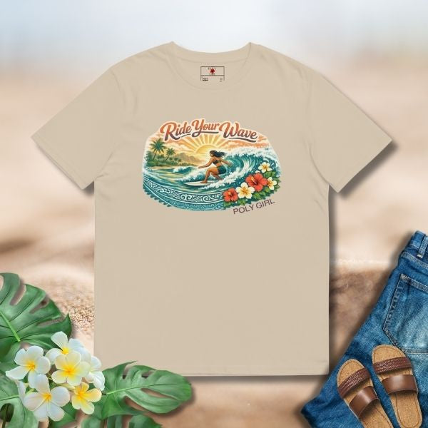 Beige tee featuring an island surf illustration with a woman riding a wave, tropical florals, sun, and Poly Girl logo.