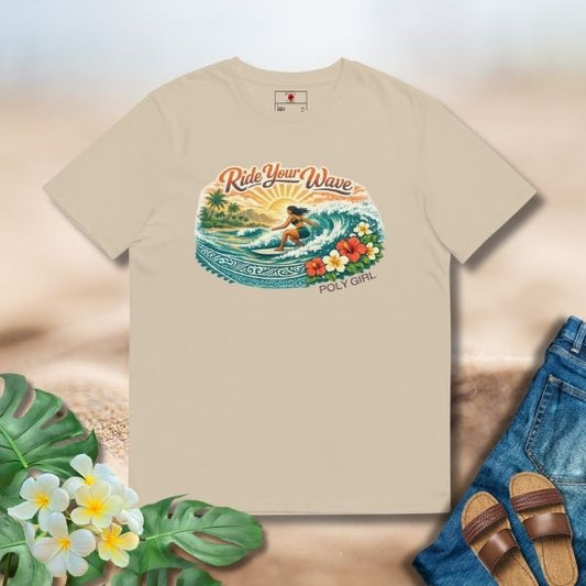 Beige tee featuring an island surf illustration with a woman riding a wave, tropical florals, sun, and Poly Girl logo.