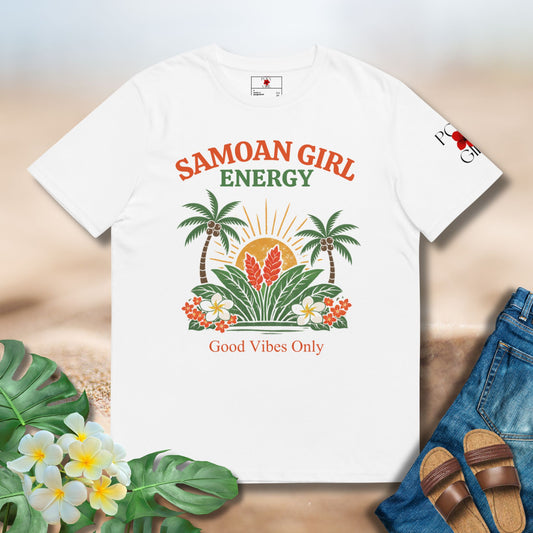 White t-shirt with 'Samoan Girl Energy' design on a sandy surface with flowers and jeans.