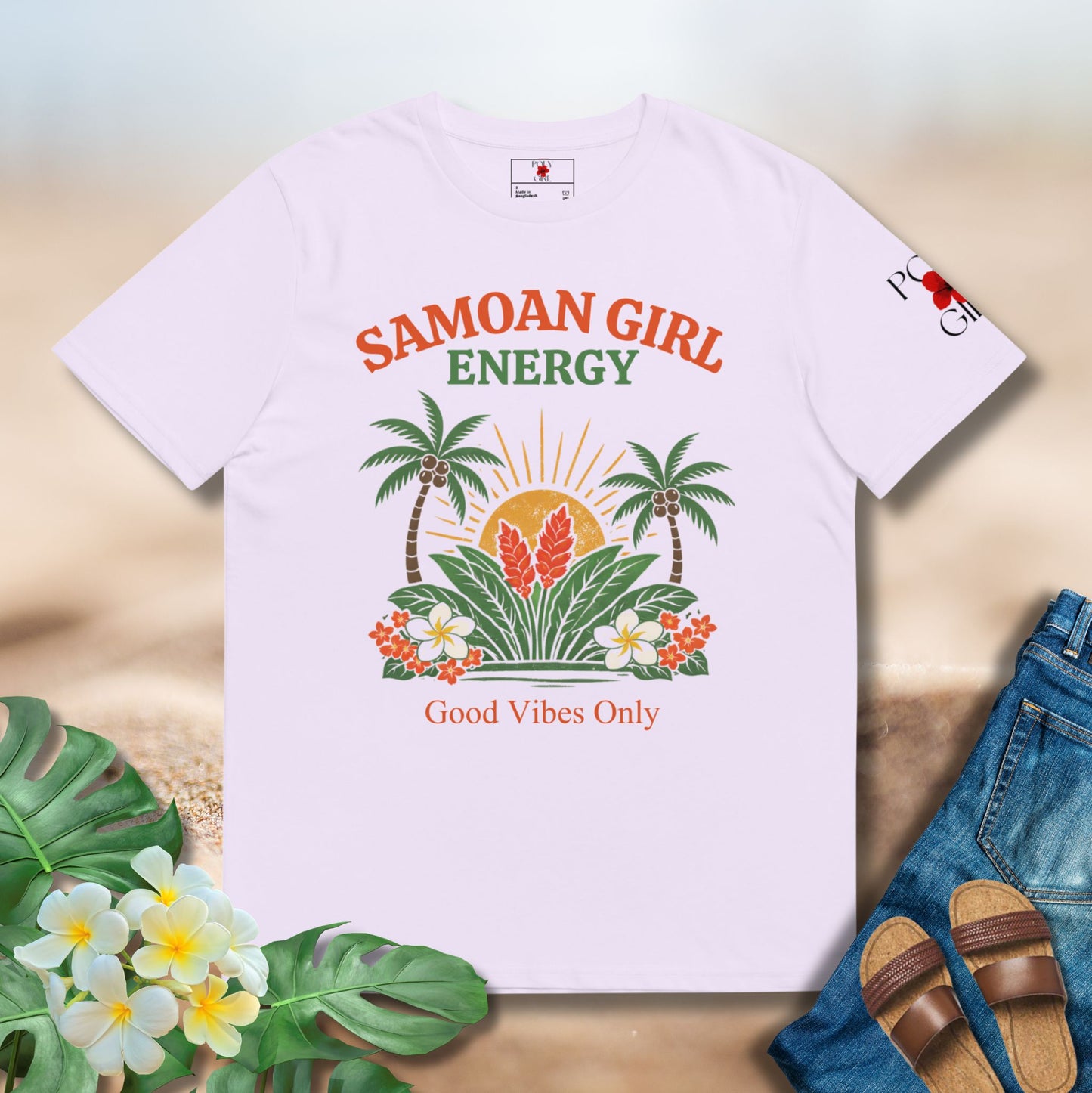 Lavender t-shirt with 'Samoan Girl Energy' design on a sand surface with flowers and sandals.