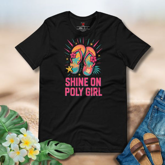 Black t-shirt with colorful flip-flop design and 'Shine On Poly Girl' text, placed on a surface with flowers and jeans.
