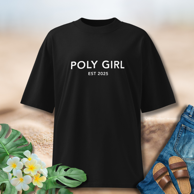 Black t-shirt with 'POLY GIRL EST 2025' text, placed on a surface with flowers and jeans.