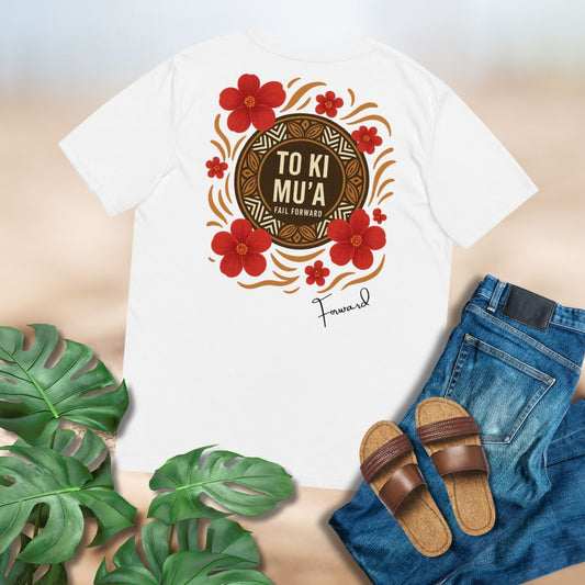 White t-shirt with a decorative design featuring red flowers and text of To Ki Mu'a on back of shirt placed on flat surface with jeans and sandals.