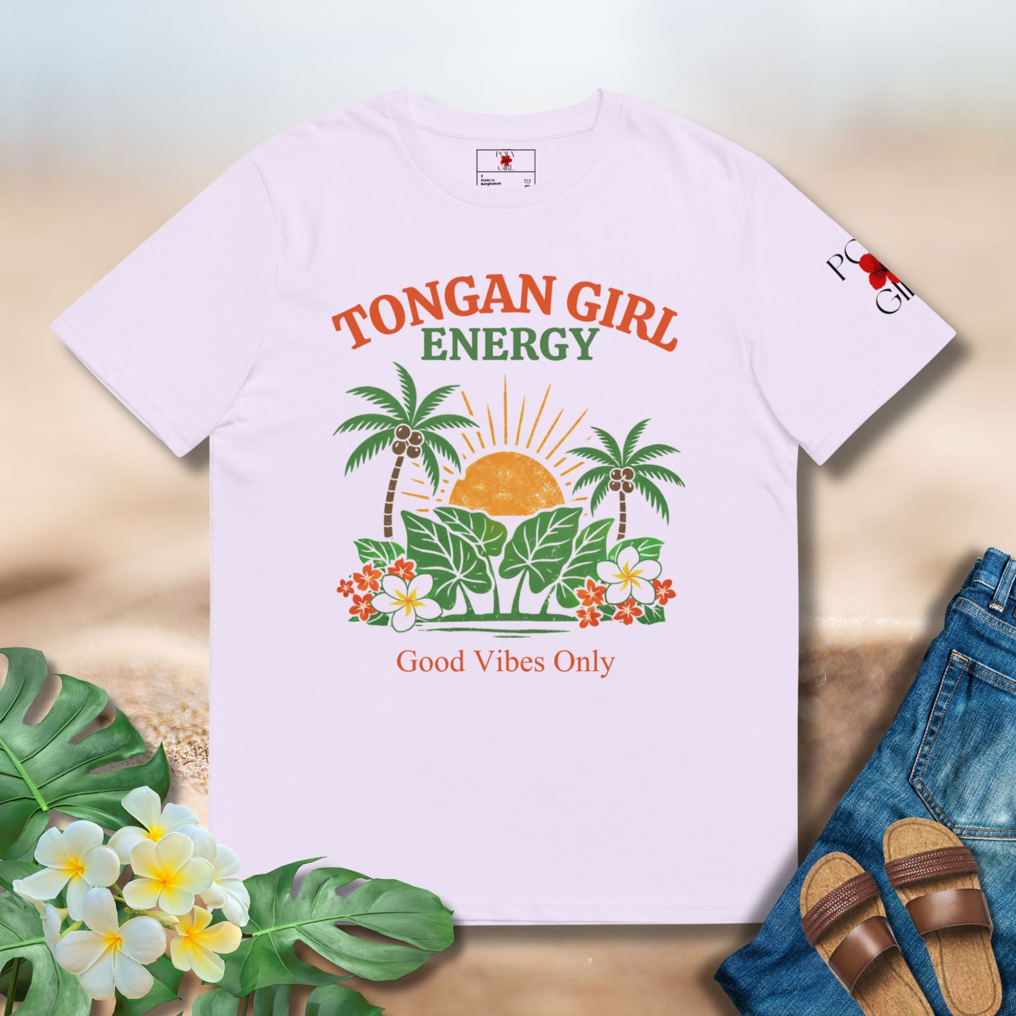 Lavender t-shirt with 'Tongan Girl Energy' design on a wooden surface with flowers and sandals.