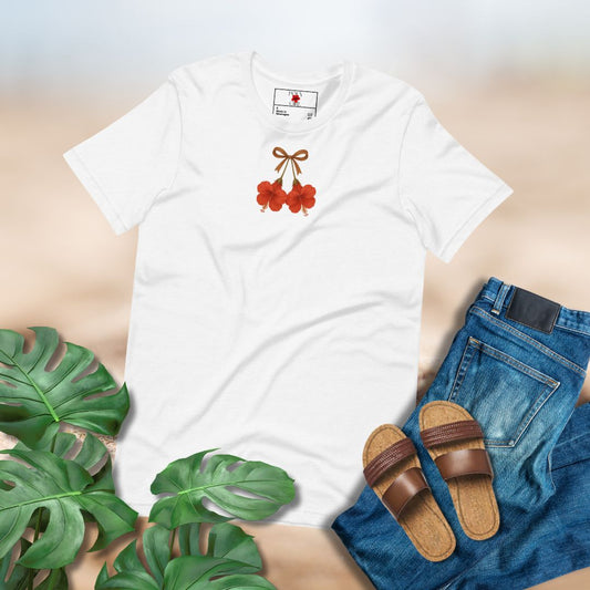 White t-shirt with two red hibiscuses design, blue jeans, brown sandals, and green leaves on a light background