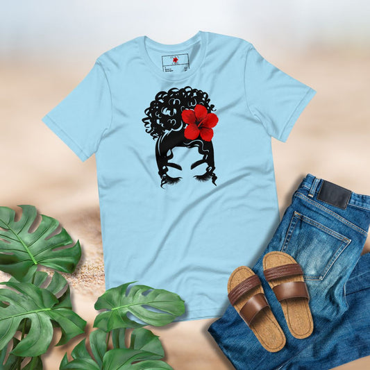 Light blue t-shirt with a woman with and updo and red hibiscus sei in her hair design, paired with jeans and sandals on a neutral background.