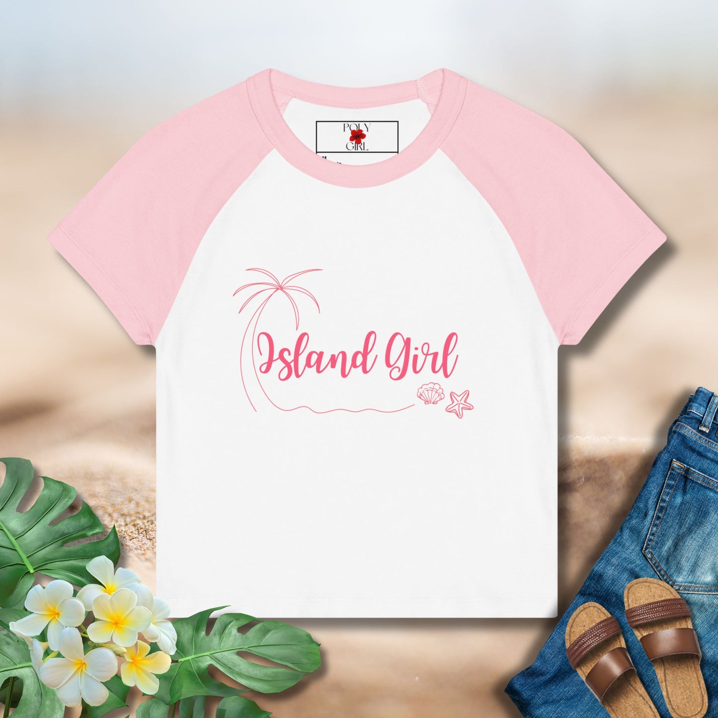 Pink and white t-shirt with 'Island Girl' text on a wooden surface with flowers and sandals.