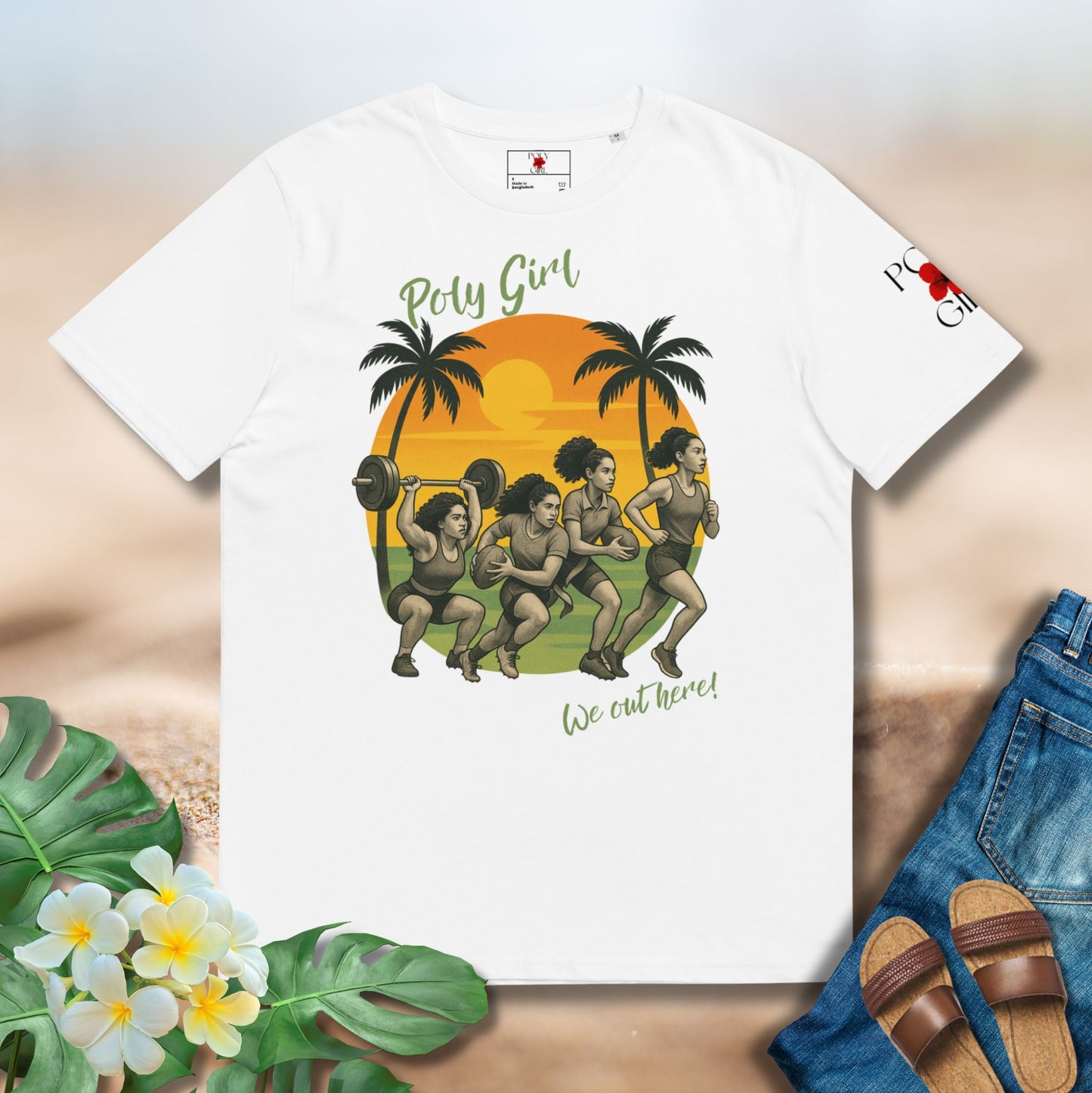 White t-shirt with a graphic design of four women athletes, palm trees, and a sunset on a beige surface with flowers and jeans.